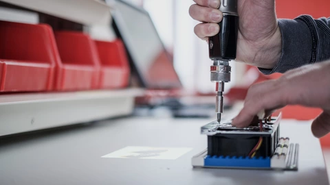 Hände mit einem Schraubendreher an einem Arbeitsplatz in den Erfurter Werkstätten