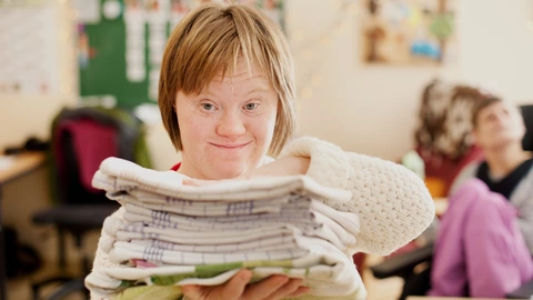 Eine Frau aus dem Förderzentrum mit einem Stapel Handtücher