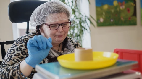 Eine Frau aus dem Förderzentrum stellt etwas auf eine Waage.