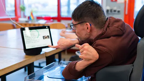 Eine Person im Rollstuhl bedient die Digitale Sprachassistenz Alexa.