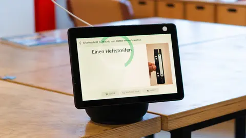 Ein Alexa-Gerät steht auf einem Tisch. Auf dem Bildschirm steht "Einen Heftstreifen"