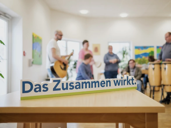 Eine Gruppe aus dem Förderzentrum musiziert zusammen. Im Vordergrund steht der Schriftzug "Das Zusammen wirkt."