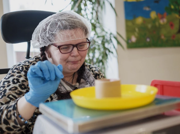 Eine Frau aus dem Förderzentrum stellt etwas auf eine Waage.