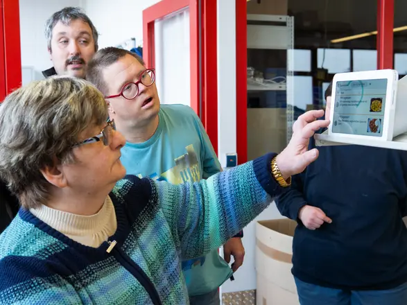 Drei Personen stehen vor einem Alexa-Gerät. Eine Frau berührt den Bildschirm.