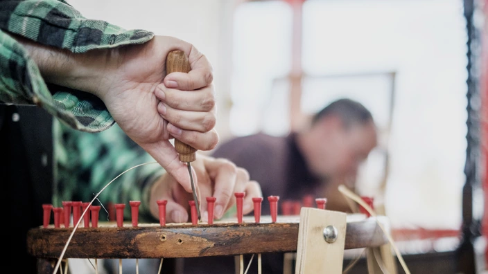 Hände beim Flechten einer Stuhlfläche