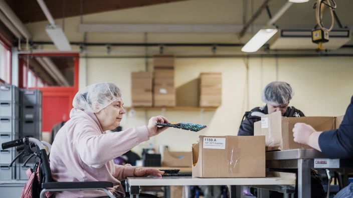 Einblick in die Erfurter Werkstätten. Eine Frau im Rollstuhl an ihrem Arbeitsplatz