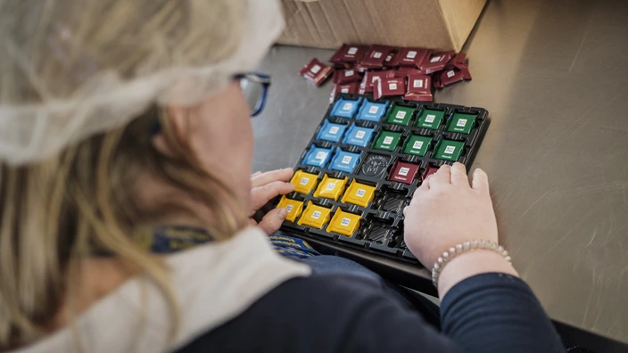 Eine Mitarbeiterin an ihrem Arbeitsplatz in den Erfurter Werkstätten. Sie befüllt einen Adventskalender.